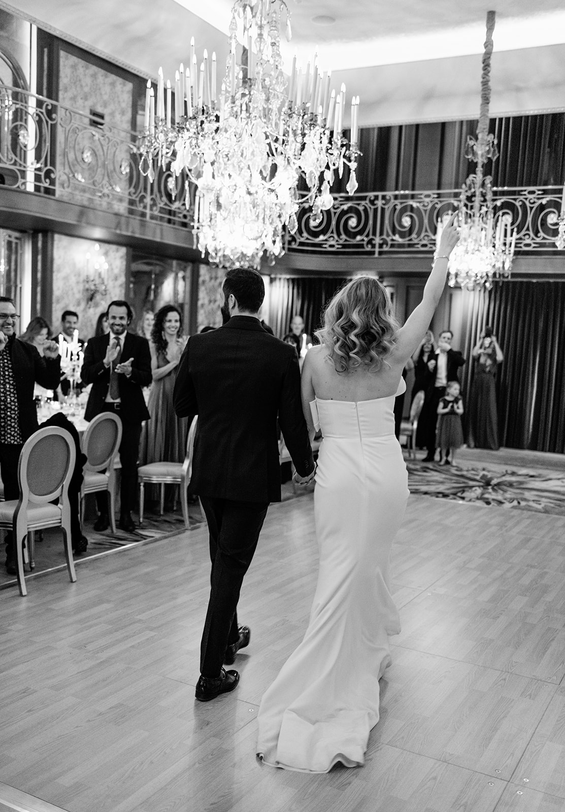 Bride and groom walking into the Plaza Athénée ballroom as guests applaud